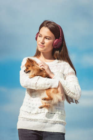 14 years girl in a wireless headphones listening to a music from a smart phone on a beach. against a blue sky. close upの写真素材