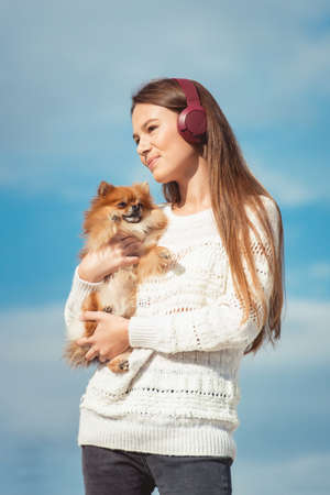14 years girl in a wireless headphones listening to a music from a smart phone on a beach. against a blue sky. close upの写真素材