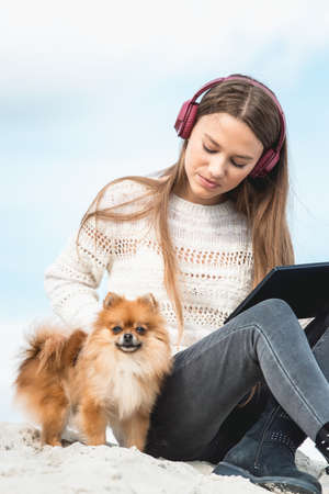 14 years girl in a wireless headphones listening to a music from a smart phone on a beach. against a blue sky. close upの写真素材