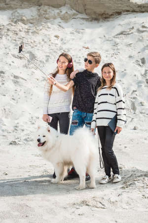 three friends with a doog breed samoyed makind selphie on a beachの写真素材