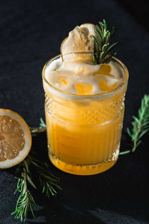 Cold Whiskey Sour Cocktail with ice and apple chips, piece of thyme on topの写真素材