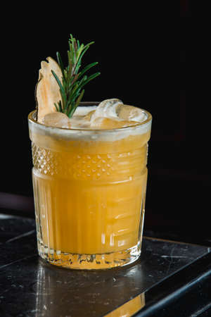 Cold Whiskey Sour Cocktail with ice and apple chips, piece of thyme on topの写真素材