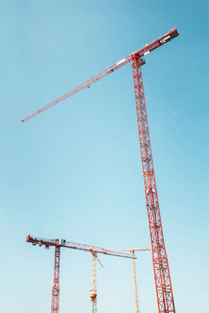 three hoisting cranes isolated on clear blue sky backgroundの写真素材