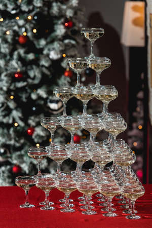 Champagne tower on a red table with Christmas tree in the backgroundの写真素材