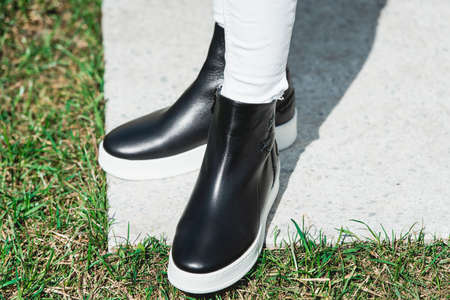 Top View Of Woman's Black Leather Ankle Boots. Outdoor Shot Over White Stone in park. white soleの写真素材