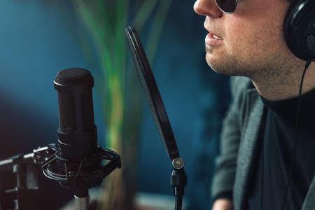 Close up of a man singer in a headphones recording a song in a home studioの写真素材