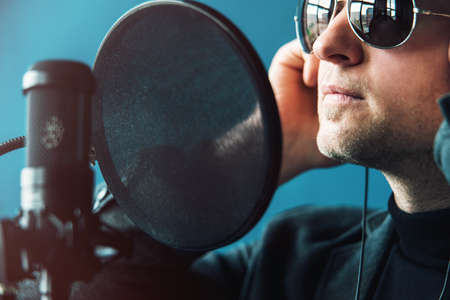 Close up of a man singer in a headphones recording a song in a home studioの写真素材