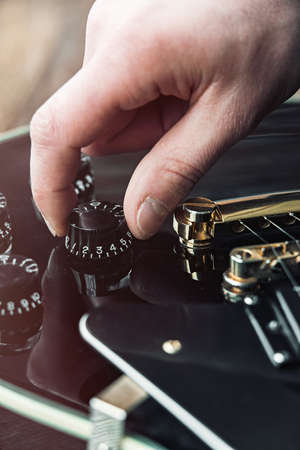 Male hand changing electric guitar settings. Tuning a timbre regulatorの写真素材