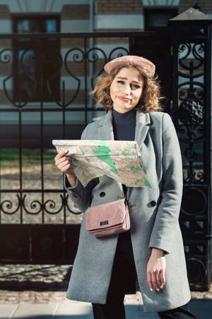 Cute young beautiful curly confused caucasian travelling woman reading a map.の写真素材