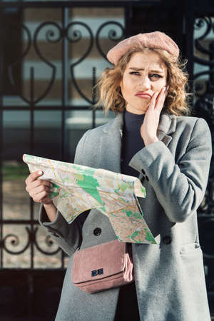 Cute young beautiful curly confused caucasian travelling woman reading a map.の写真素材