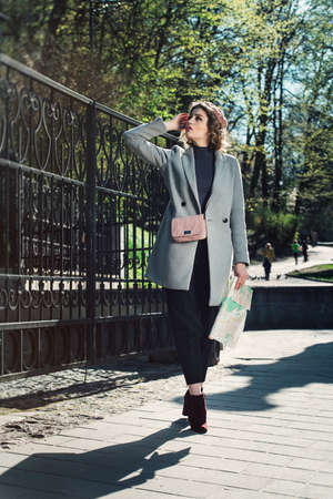 Cute young beautiful curly confused caucasian travelling woman reading a map.の写真素材