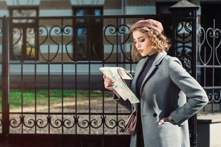 Cute young beautiful curly confused caucasian travelling woman reading a map.の写真素材