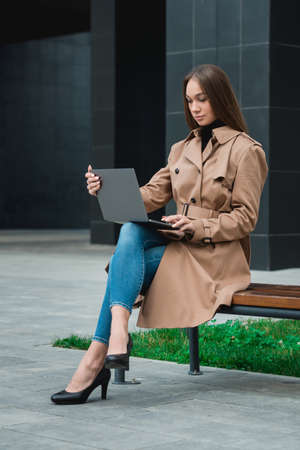 Young business woman controlling bussines from notebook. Internet business management concept. Working outdoorの写真素材