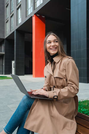 Young business woman controlling bussines from notebook. Internet business management concept. Working outdoorの写真素材