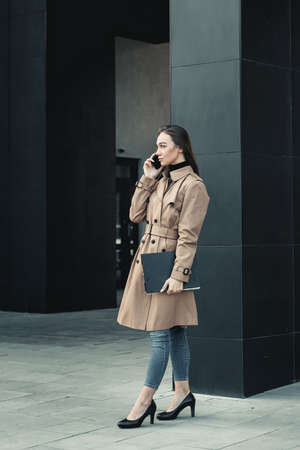 Self-confidence young business woman with file in a hand. outdoor. cityscapeの写真素材