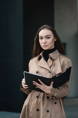 Self-confidence young business woman with file in a hand. outdoor. cityscapeの写真素材