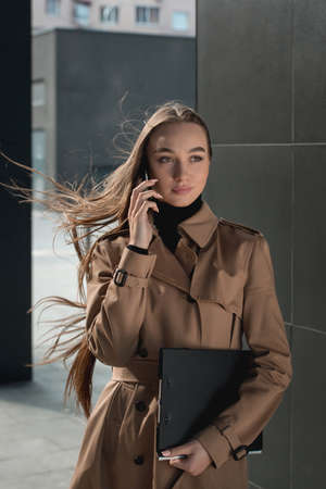 Self-confidence young business woman with file in a hand. outdoor. cityscapeの写真素材