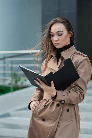 Self-confidence young business woman with file in a hand. outdoor. cityscapeの写真素材