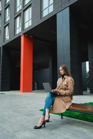 Young business woman controlling bussines from notebook. Internet business management concept. Working outdoorの写真素材