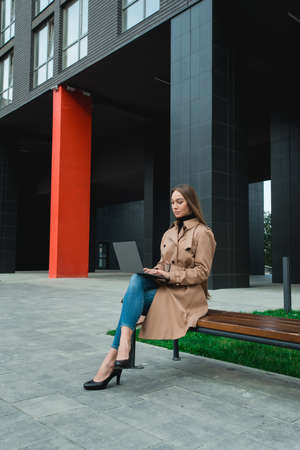Young business woman controlling bussines from notebook. Internet business management concept. Working outdoorの写真素材