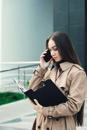 Self-confidence young business woman with file in a hand. outdoor. cityscapeの写真素材