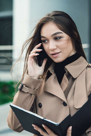 Self-confidence young business woman with file in a hand. outdoor. cityscapeの写真素材
