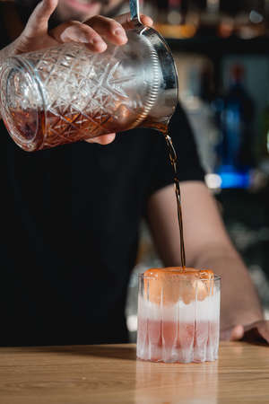Bartender pouring alcohol boulevardie cocktail on a bar desk. black background.の写真素材