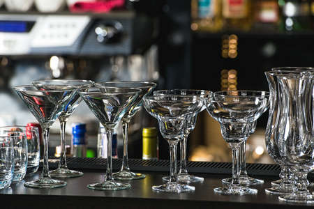 Glasses for a margarita, martini, grog and liqueur on a bar at restaurant, against the bar bar wall background.の写真素材