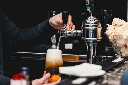 bartender pours a glass of light beer.