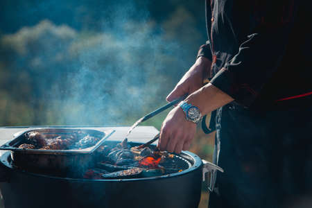 meat grilling over the coals on a portable barbecue with vegetablesの写真素材