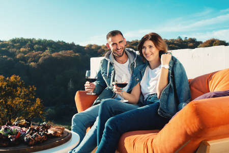 young couple celebrating the purchase of a new home. Smiling husband and wife with glasses of red wine in handsの写真素材