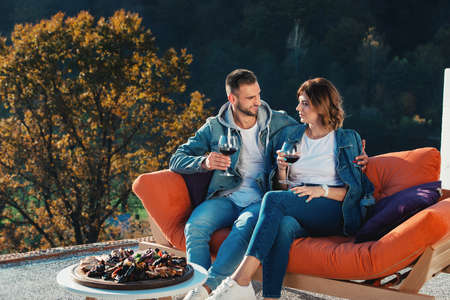 young couple celebrating the purchase of a new home. Smiling husband and wife with glasses of red wine in handsの写真素材
