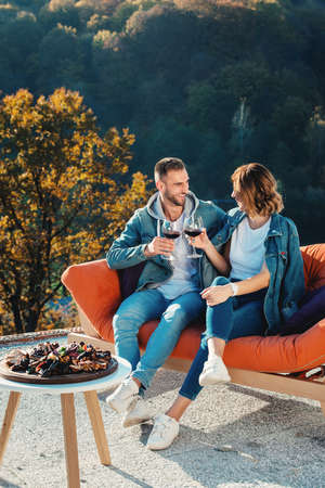 young couple celebrating the purchase of a new home. Smiling husband and wife with glasses of red wine in handsの写真素材