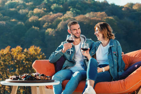 young couple celebrating the purchase of a new home. Smiling husband and wife with glasses of red wine in handsの写真素材