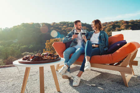 young couple celebrating the purchase of a new home. Smiling husband and wife with glasses of red wine in handsの写真素材