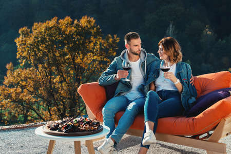 young couple celebrating the purchase of a new home. Smiling husband and wife with glasses of red wine in handsの写真素材