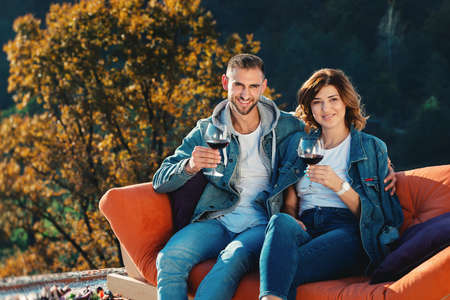 young couple celebrating the purchase of a new home. Smiling husband and wife with glasses of red wine in handsの写真素材