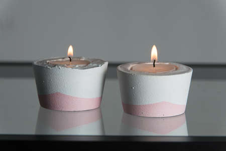Two candles in white and pink concrete candle holders.の写真素材