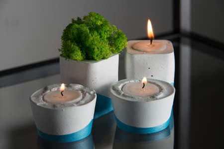 candles and moss in white and blue concrete candle holders.の写真素材