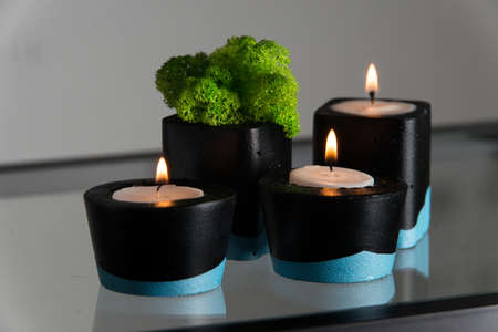 Candles and moss in black and blue concrete candle holders.の写真素材