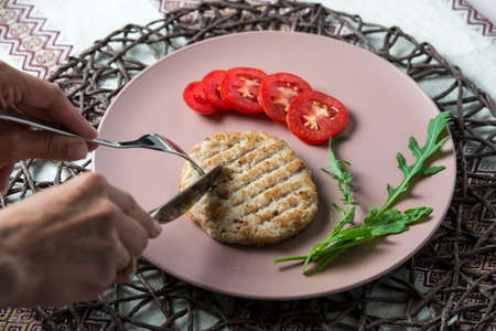 woman eats juicy fried meat cutlet with tomato on a plate.の写真素材