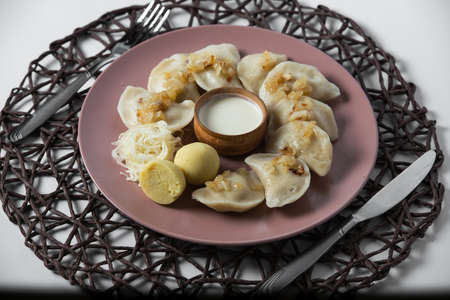 dumplings with stewed cabbage and fried onion, homemade traditional Ukrainian dish varenyky with sour creamの写真素材