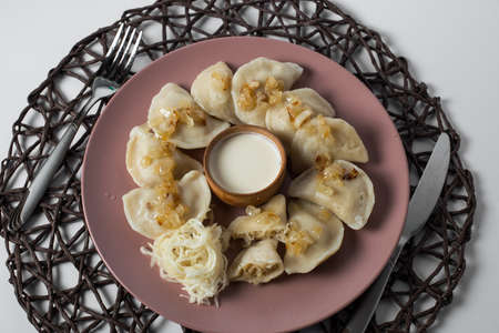 dumplings with stewed cabbage and fried onion, homemade traditional Ukrainian dish varenyky with sour creamの写真素材