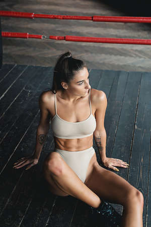 Fashionable brunette girl in a biege underwear posing on a floor in a boxing ringの写真素材