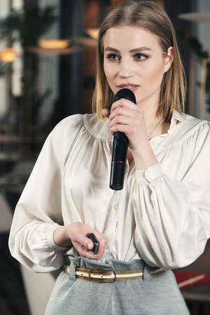 Business and speech topic: woman in a white blouse holding a black microphone, indoorの写真素材
