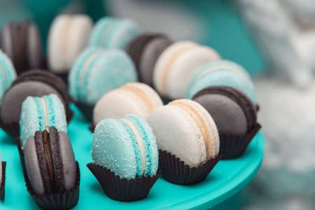 Light cream, blue and chocolate macaroons on blue stand. Food knolling concept.の写真素材