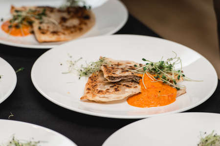 Uzbek eastern Tatar cuisine, cheburek with meat on a white plate with microgreen and sauce