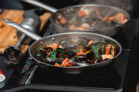 Chief in a restaurant cooking seafood with sauce on a frying panの写真素材