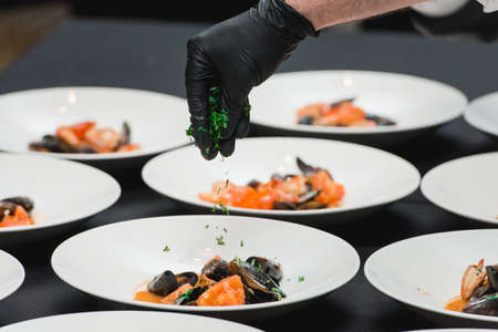 Chief in a restaurant serving seafood with sauce on a plateの写真素材