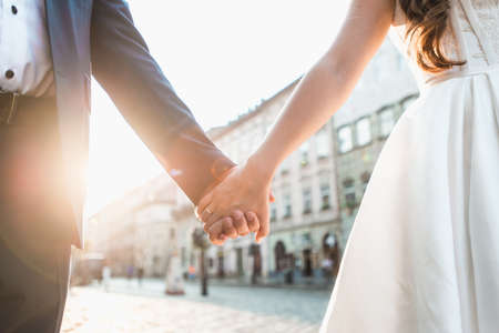 Wedding couple holding hands on sunset background.の写真素材